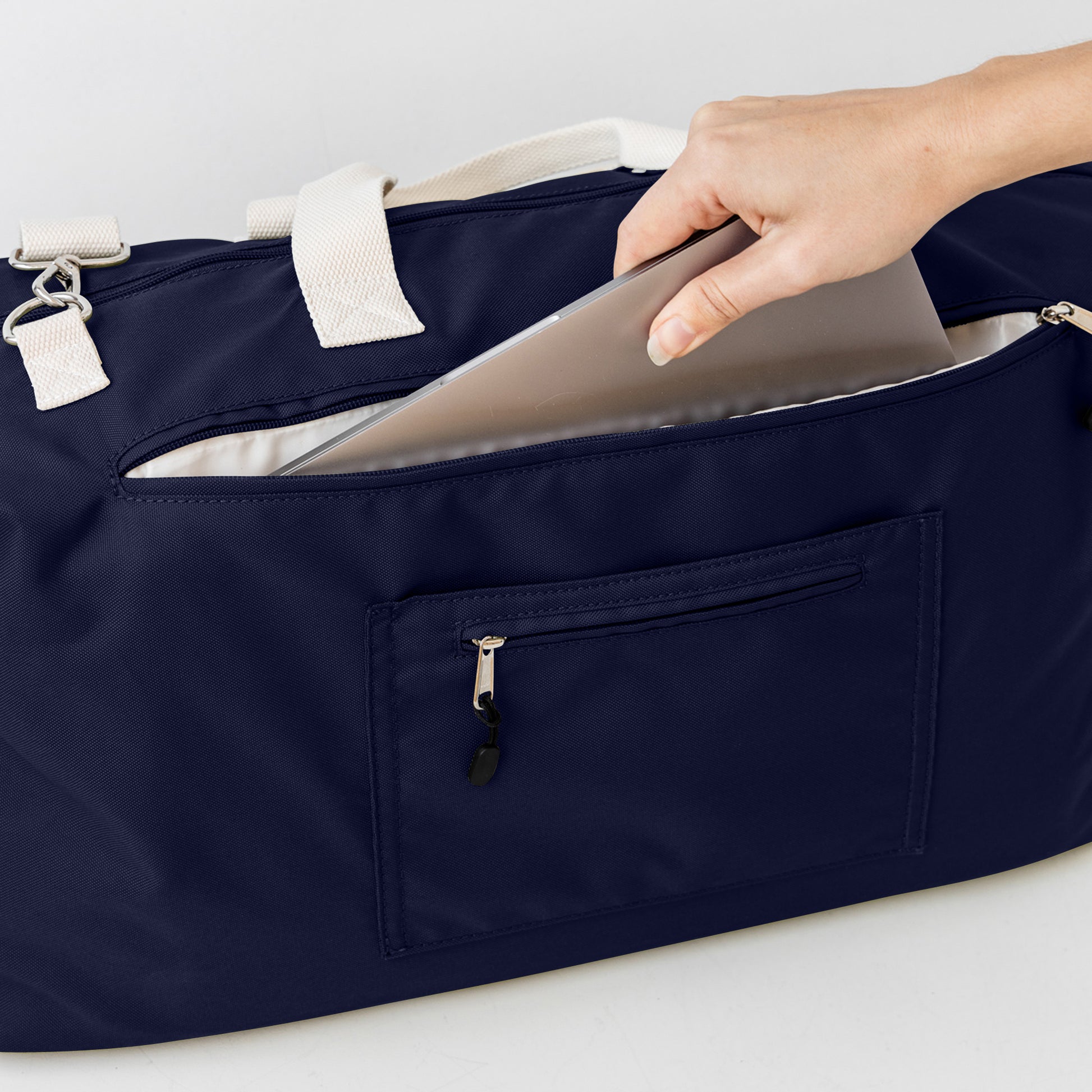 Navy duffle bag back showing padded laptop pocket and passport pocket