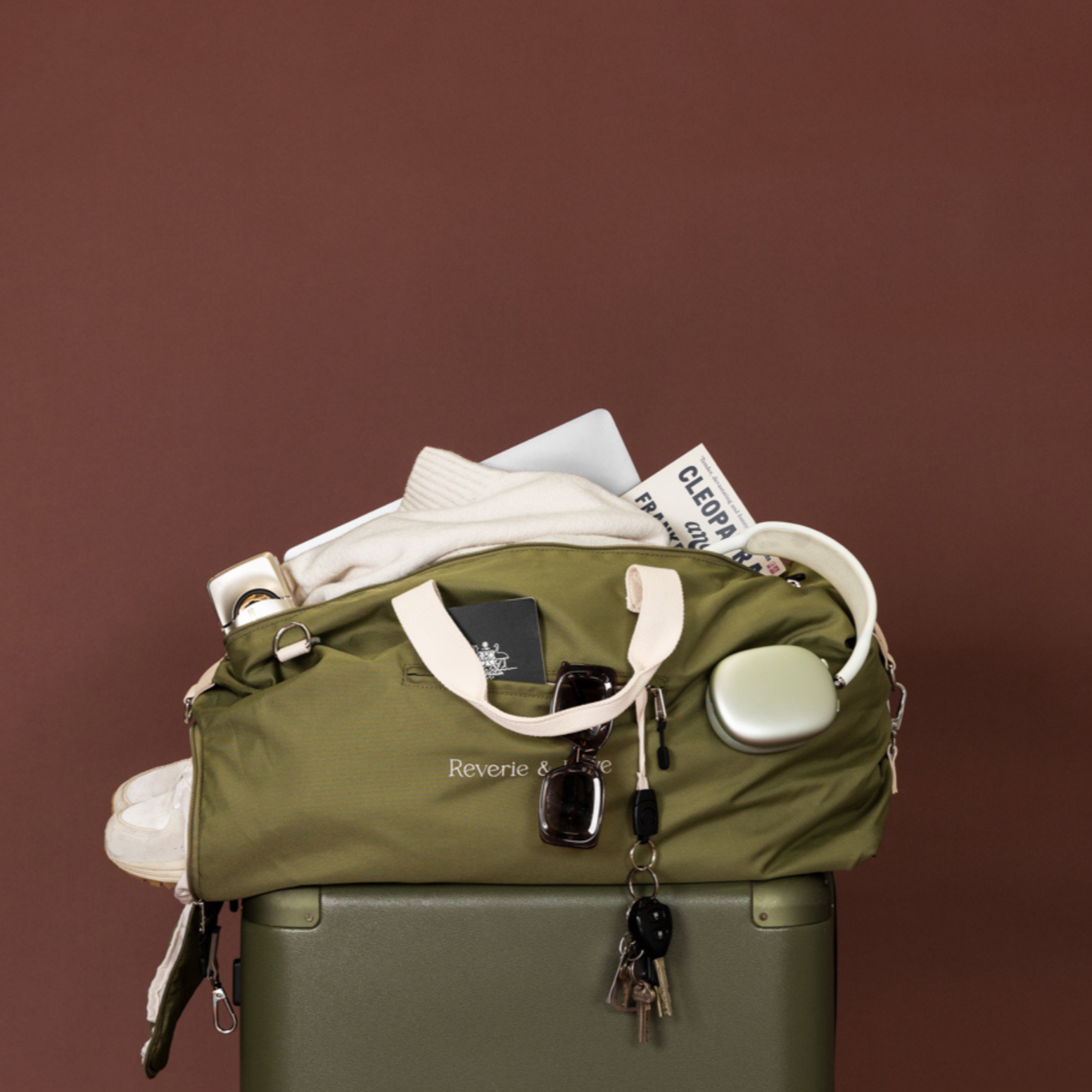 Olive green duffle bag packed for travel on top of suitcase