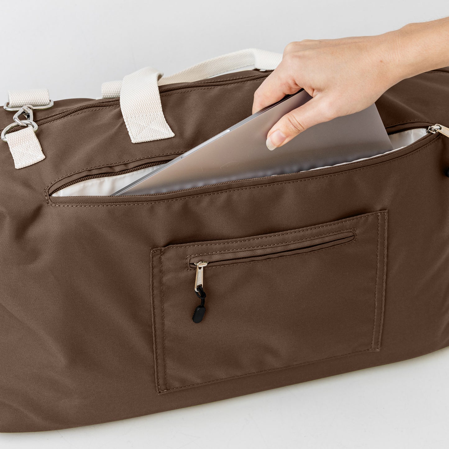 Chocolate duffle bag back showing padded laptop section and secret passport pocket