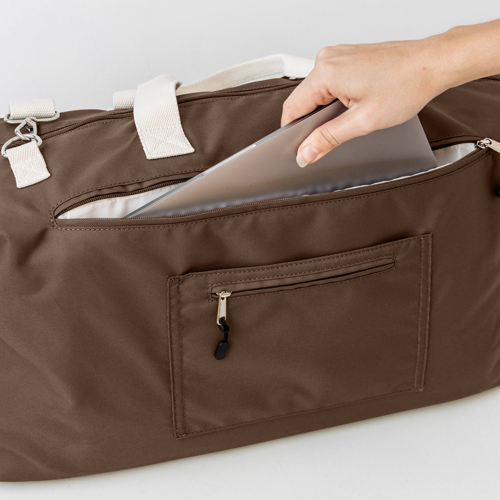 Chocolate duffle bag back showing padded laptop section and secret passport pocket
